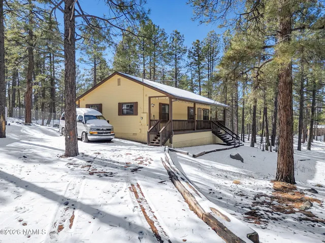 a view of a house with trees and covered with snow in the background
