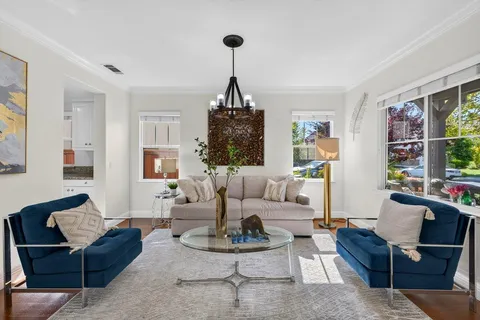 a living room with furniture a rug a table and a chandelier