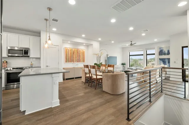 a kitchen with a sink dishwasher a stove and a dining table with wooden floor