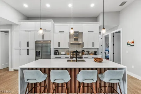 a kitchen with stainless steel appliances granite countertop a dining table chairs and a refrigerator