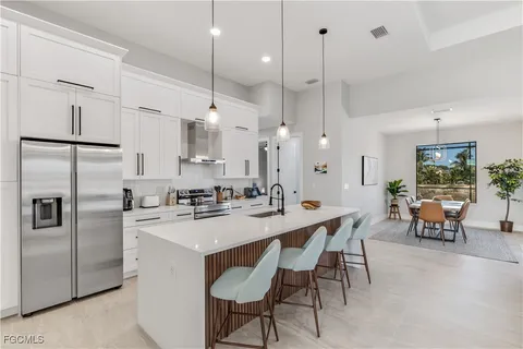 a kitchen with stainless steel appliances kitchen island granite countertop a table chairs and a refrigerator