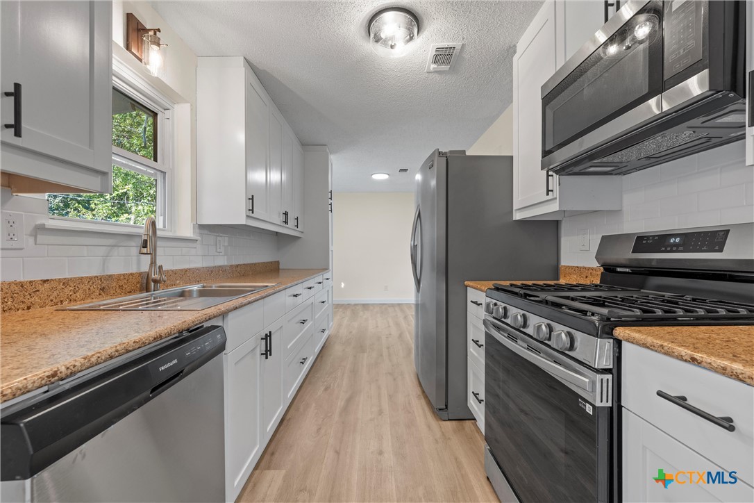914 Edwards Street Copperas Cove, TX 76522 - Photo 3 of 13 a kitchen with stainless steel appliances granite countertop a sink stove and refrigerator