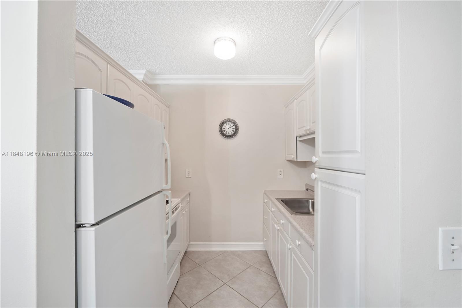 900 Atlantic Shores Boulevard, Unit 215 Hallandale Beach, FL 33009 - Photo 12 of 58 a kitchen with a refrigerator and white cabinets