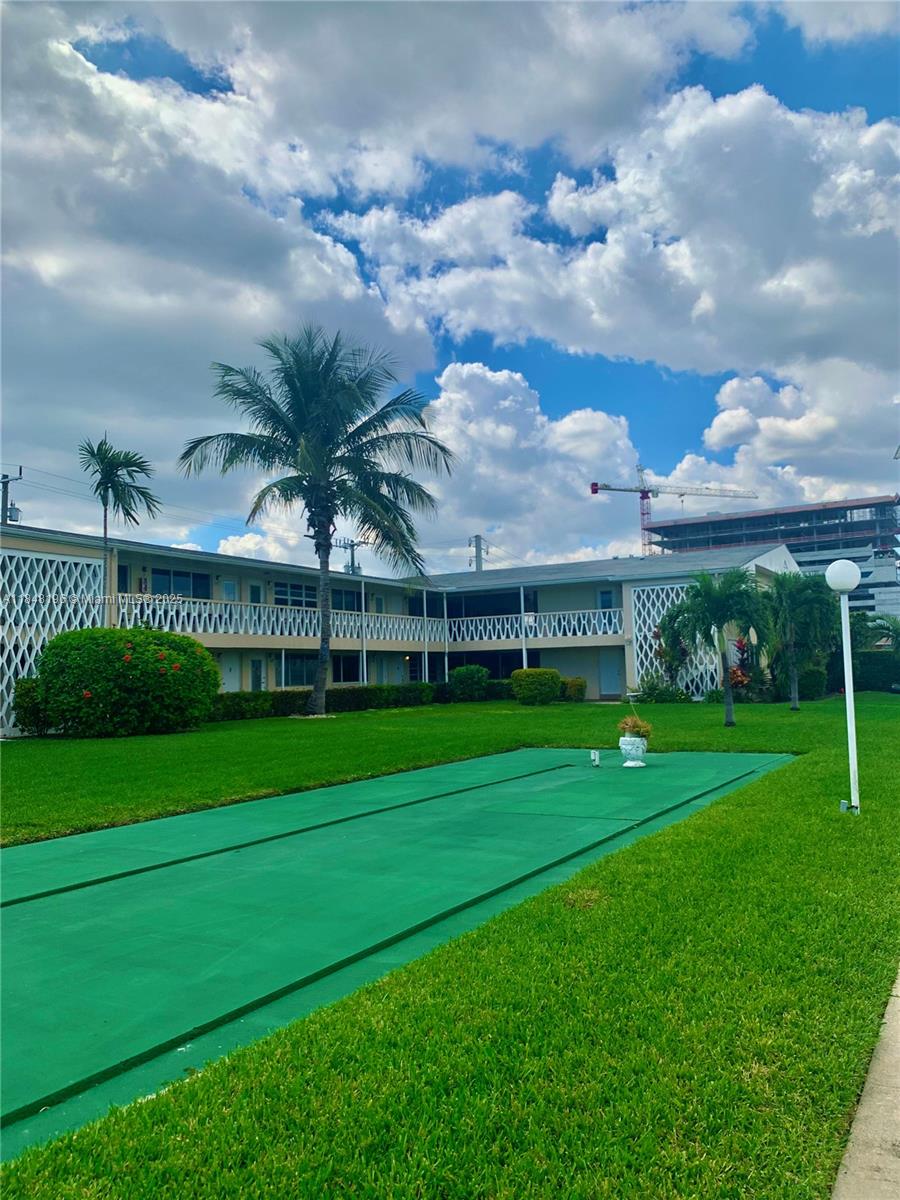 900 Atlantic Shores Boulevard, Unit 215 Hallandale Beach, FL 33009 - Photo 44 of 58 a view of a big house with a big yard and a large tree