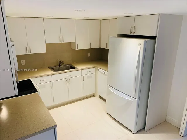 a kitchen with stainless steel appliances a refrigerator sink and white cabinets