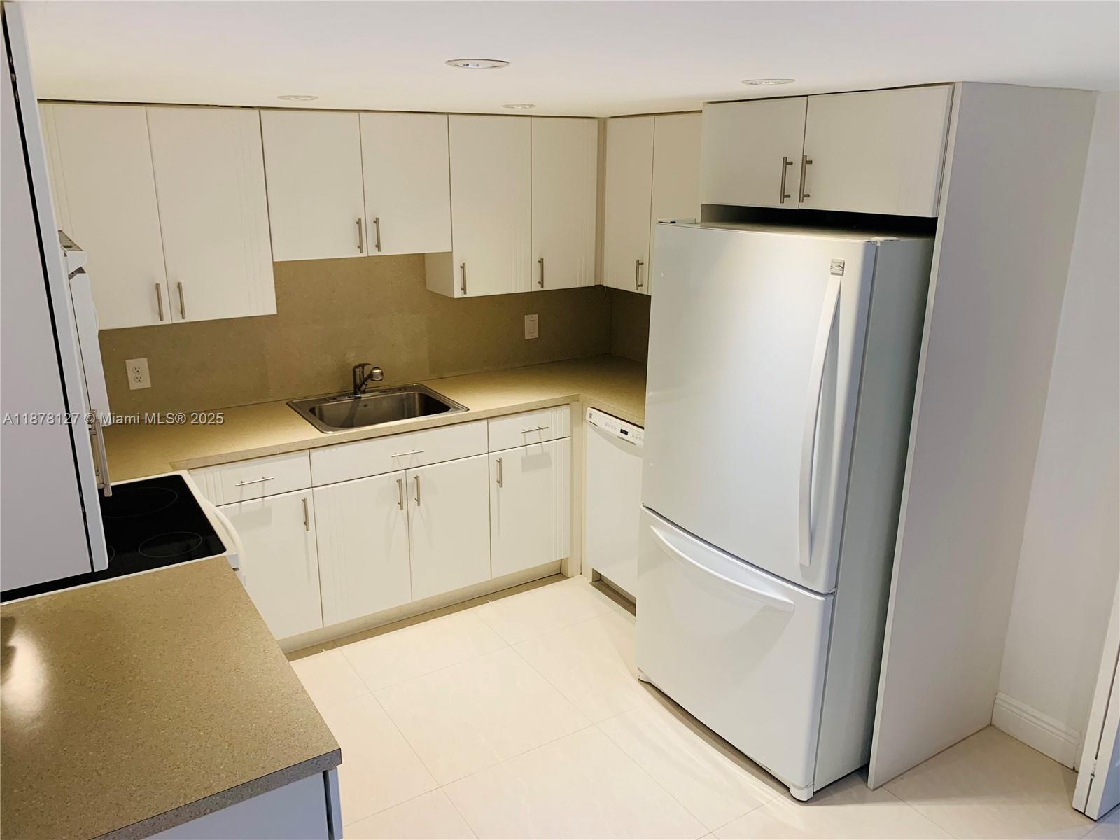 a kitchen with stainless steel appliances a refrigerator sink and white cabinets