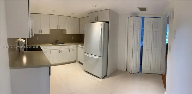 a kitchen with stainless steel appliances a refrigerator sink and white cabinets