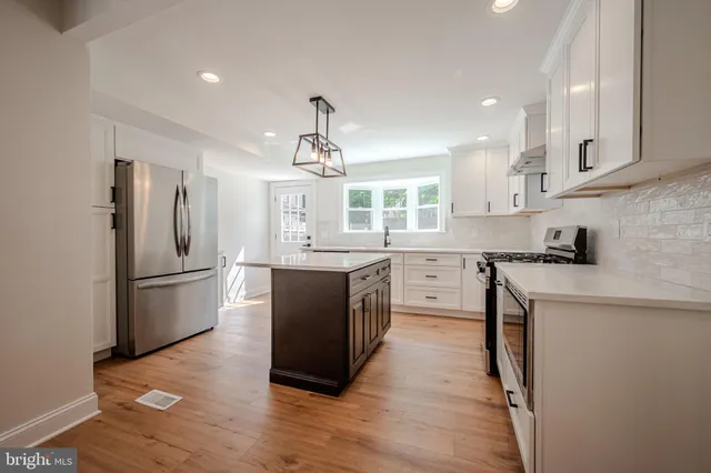 a kitchen with a refrigerator a sink dishwasher a stove and white cabinets with wooden floor