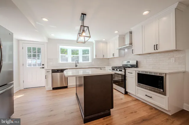 a kitchen with stainless steel appliances granite countertop a stove top oven a sink dishwasher and a refrigerator with wooden floor