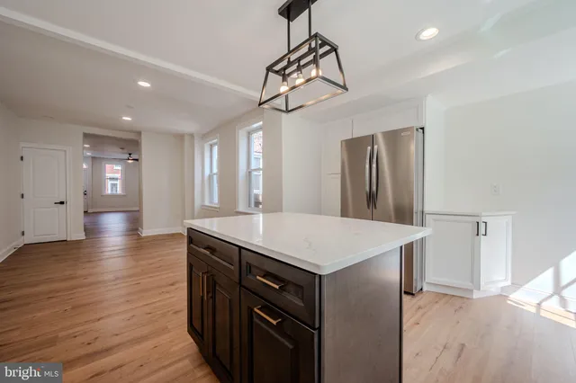 a kitchen that has a sink a center island stainless steel appliances and cabinets