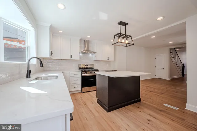 a kitchen with stainless steel appliances a sink stove and wooden floor