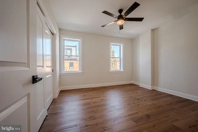 a view of empty room with wooden floor and ceiling fan