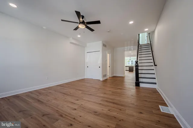 a view of an empty room with wooden floor and stairs