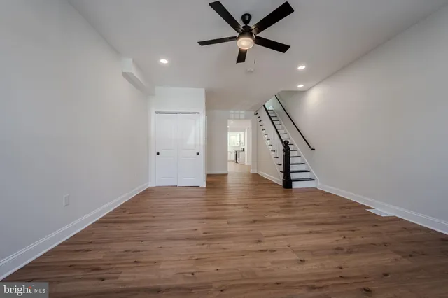 a view of an empty room with wooden floor and staircase