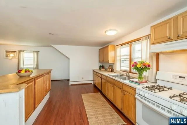 a large kitchen with stainless steel appliances granite countertop a stove and a wooden floors