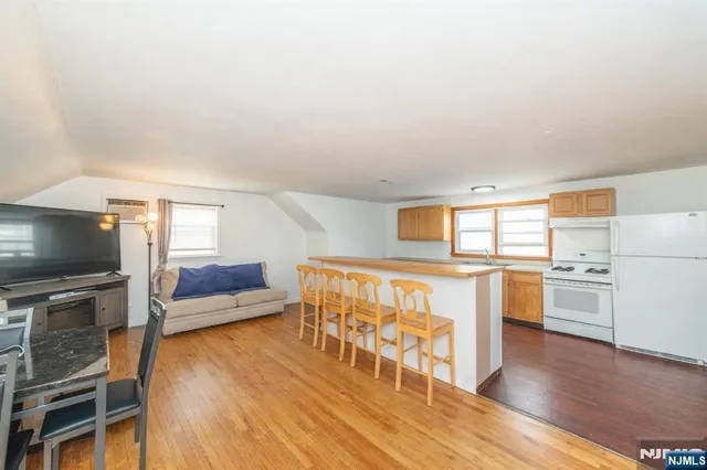 a living room with stainless steel appliances wooden floor and a flat screen tv