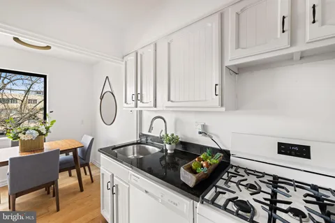 a kitchen with stainless steel appliances a sink a stove and white cabinets