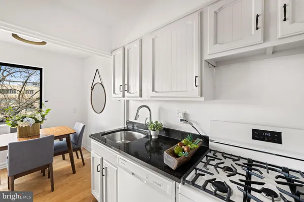 a kitchen with stainless steel appliances a sink a stove and white cabinets