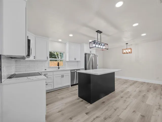 a large kitchen with stainless steel appliances kitchen island a large counter top and wooden floors