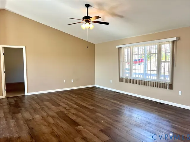 a view of an empty room with window and wooden floor
