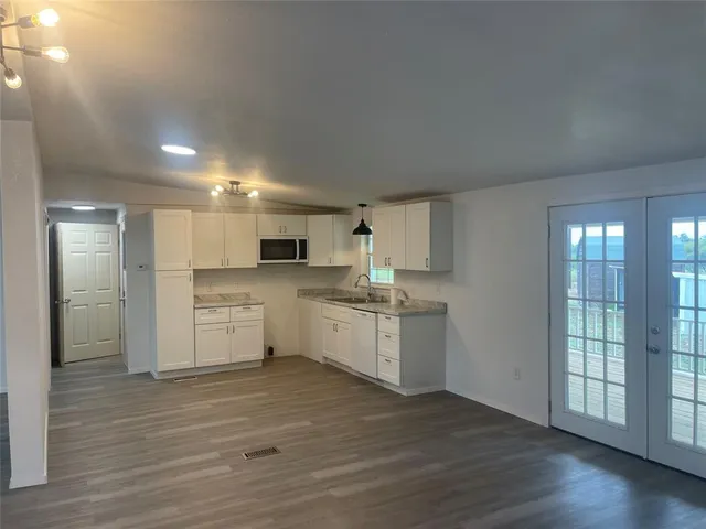 a large white kitchen with wooden floor and stainless steel appliances