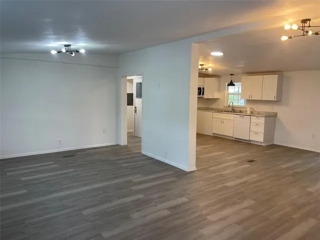 a view of a kitchen with kitchen island a sink wooden floor and a counter top space
