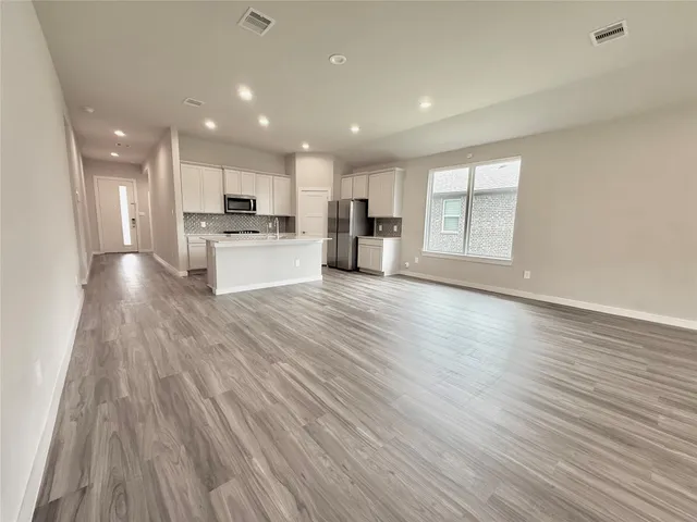 a view of large kitchen with kitchen island wooden floor center island and stainless steel appliances