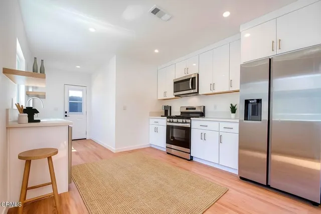 a kitchen with granite countertop a refrigerator stove top oven and sink