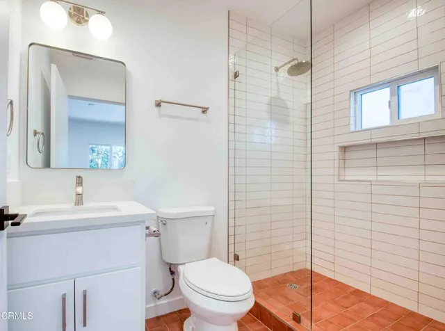 a bathroom with a sink a toilet a mirror and shower