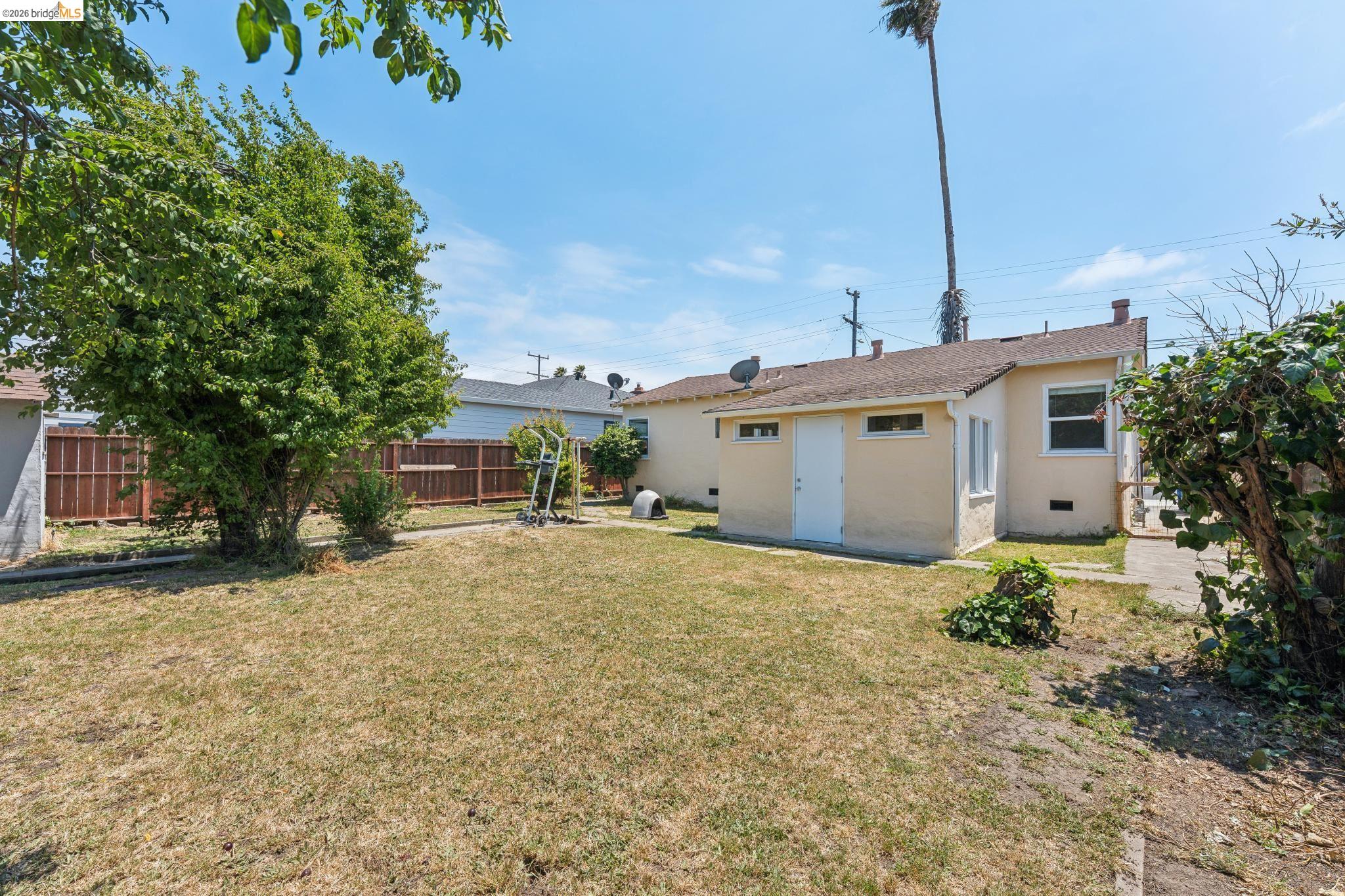 2879 Rheem Avenue Richmond, CA 94804 - Photo 36 of 45 Spacious rear yard featuring a detached structure, mature tree, concrete pathway, and perimeter fencing