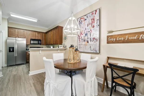 a kitchen with stainless steel appliances kitchen island granite countertop a dining table chairs and a refrigerator