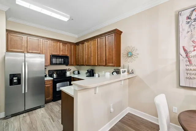 a kitchen with stainless steel appliances a sink a stove a refrigerator cabinets and a dining table