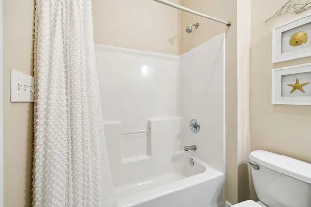 a white bath tub sitting next to a white toilet and curtain