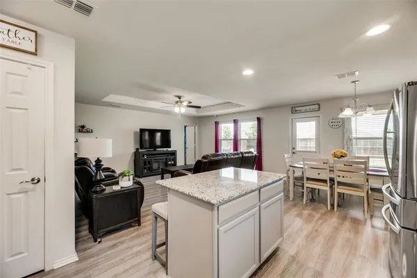 a kitchen with a stove a refrigerator and a dining table with wooden floor