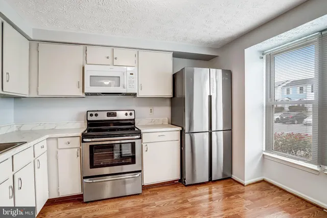 a kitchen with cabinets stainless steel appliances and wooden floor