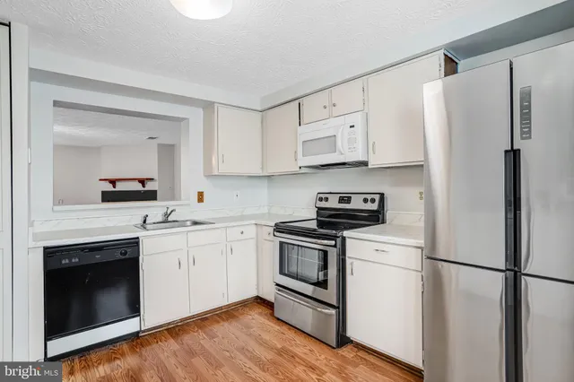 a kitchen with cabinets stainless steel appliances and wooden floor