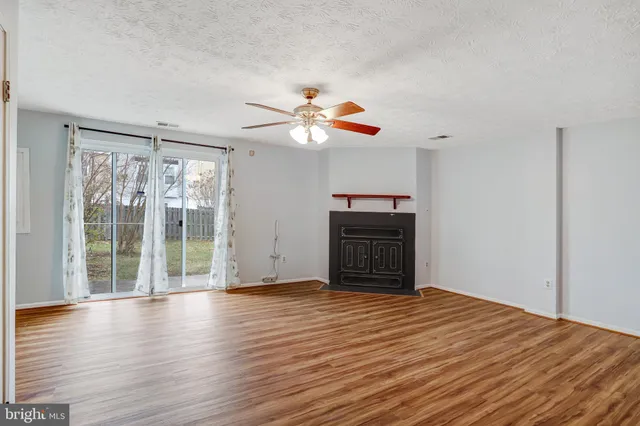 a view of a room with wooden floor and a ceiling fan
