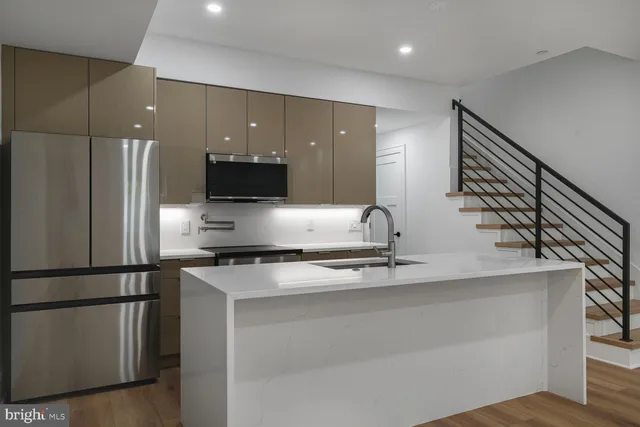 a kitchen with stainless steel appliances granite countertop a refrigerator a sink and a stove