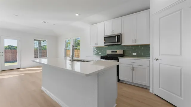 a kitchen with white cabinets and sink
