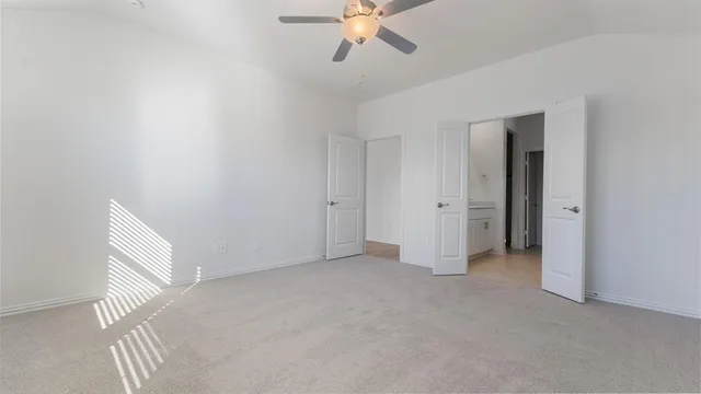 an empty room with chandelier fan and windows