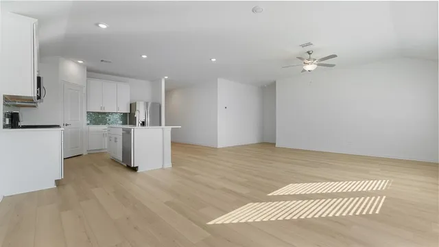 a view of kitchen with refrigerator and white cabinets