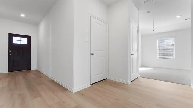 a view of an empty room with window and wooden floor