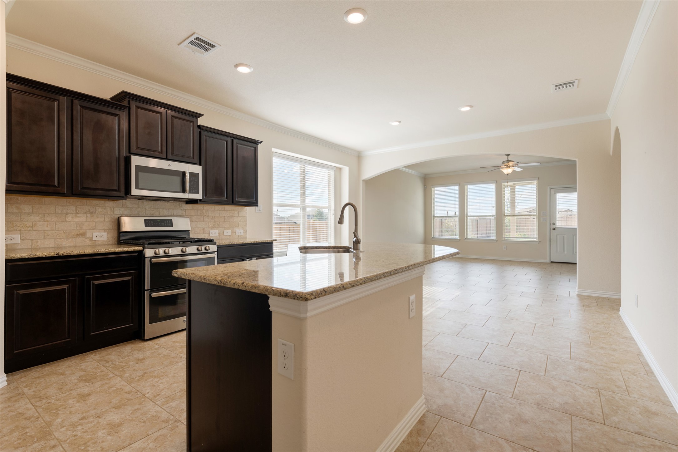 18304 Blush Rose Road Pflugerville, TX 78660 - Photo 4 of 16 Granite countertops and dark cabinetry anchor this open kitchen flowing into the living area.