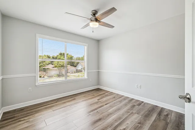 an empty room with wooden floor closet and windows