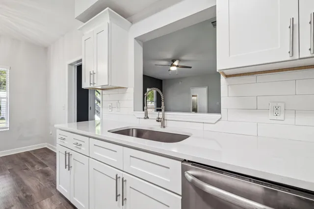 a view of an empty room with wooden floor and a ceiling fan