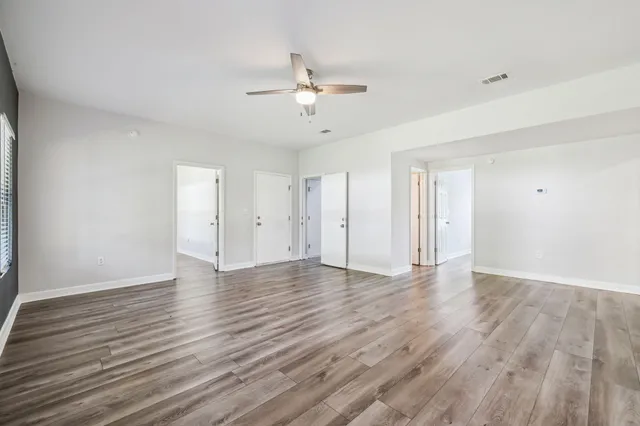a view of an empty room with wooden floor and a window