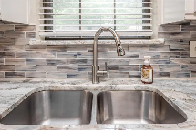 a kitchen with stainless steel appliances kitchen island granite countertop a dining table chairs and white cabinets