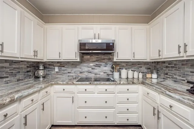 a kitchen with granite countertop white cabinets stainless steel appliances and sink