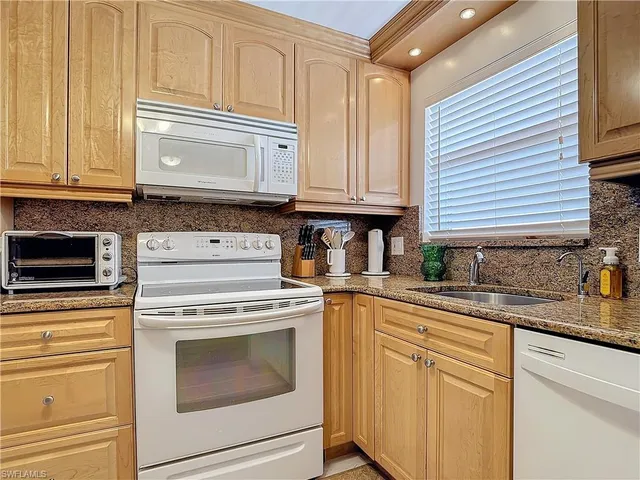 a kitchen with granite countertop cabinets stainless steel appliances and a sink