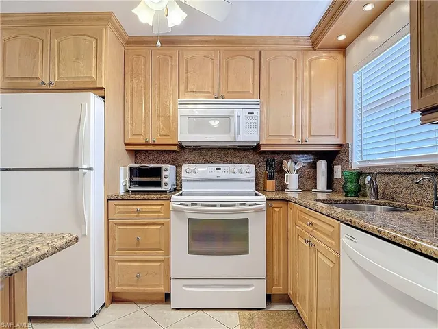 a kitchen with granite countertop a sink stove and refrigerator
